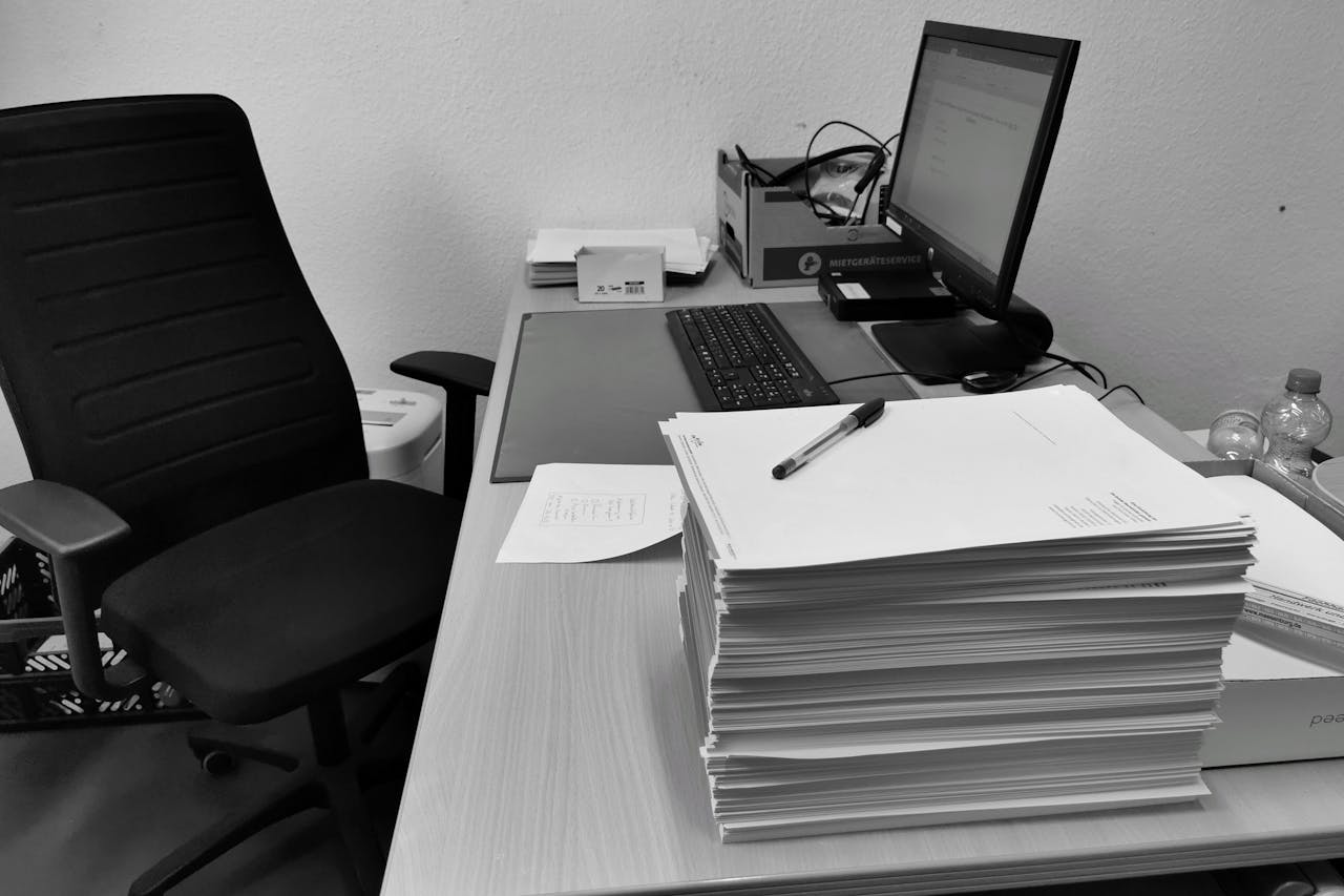 Mastering the First Impression: Your intriguing post title goes here Black and white image of a cluttered office desk with a computer, chair, and paperwork.